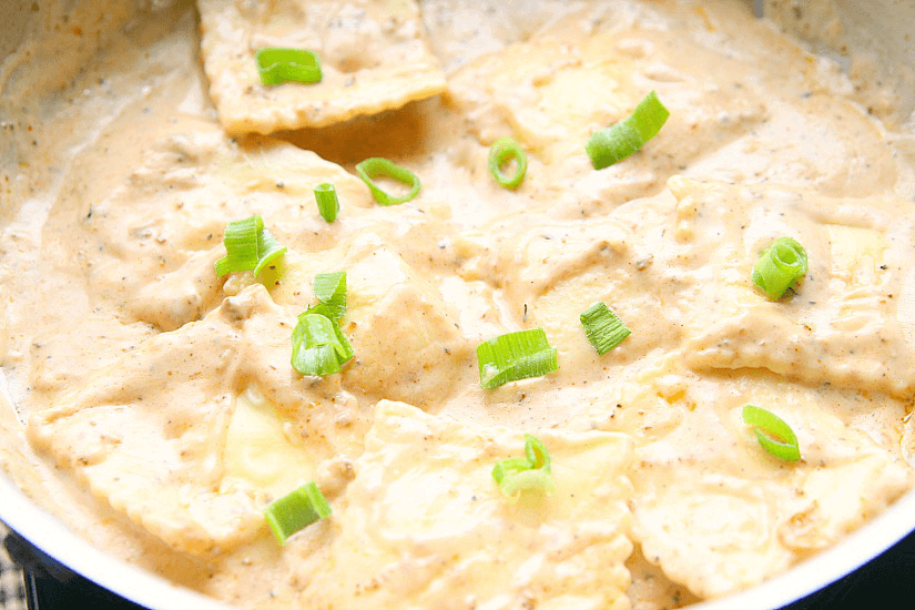 A pan with ravioli and alfredo sauce.