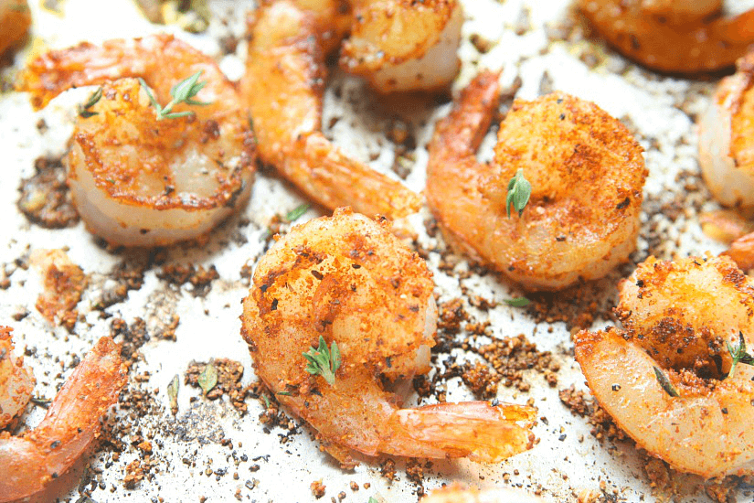 Shrimp in a pan with blackened seasonings.