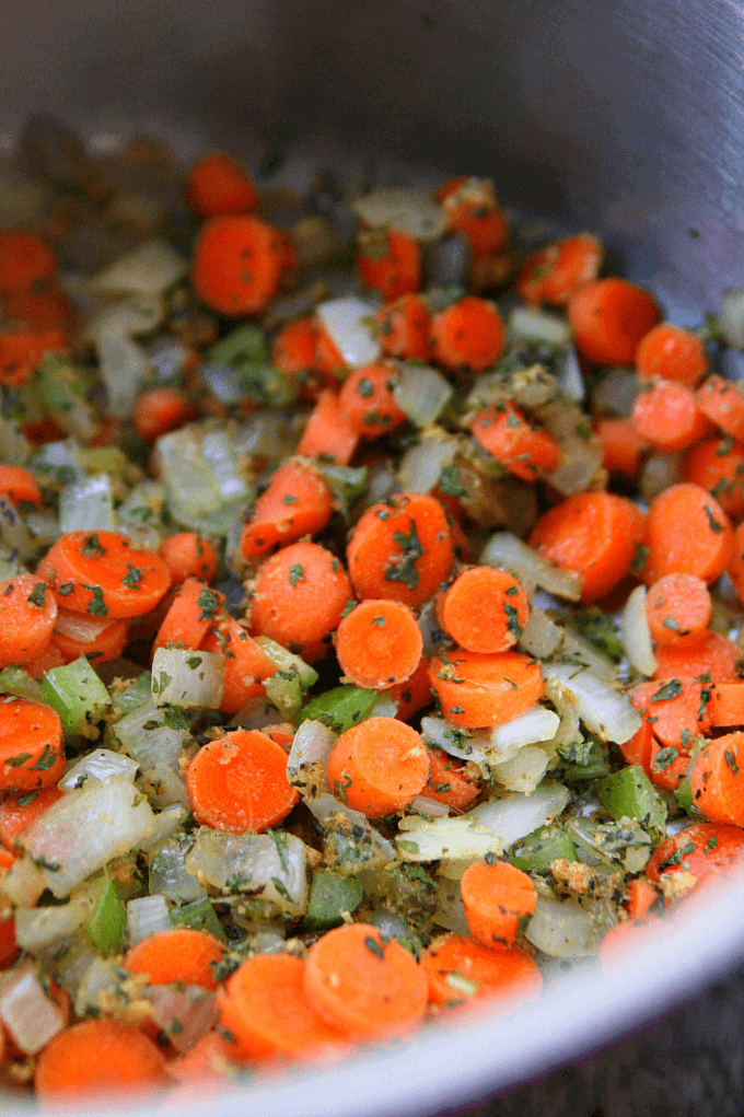 Vegetables being sautéed in a saucepan.