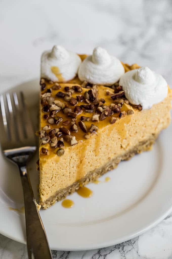Slice of pumpkin cheesecake on a plate with a fork.
