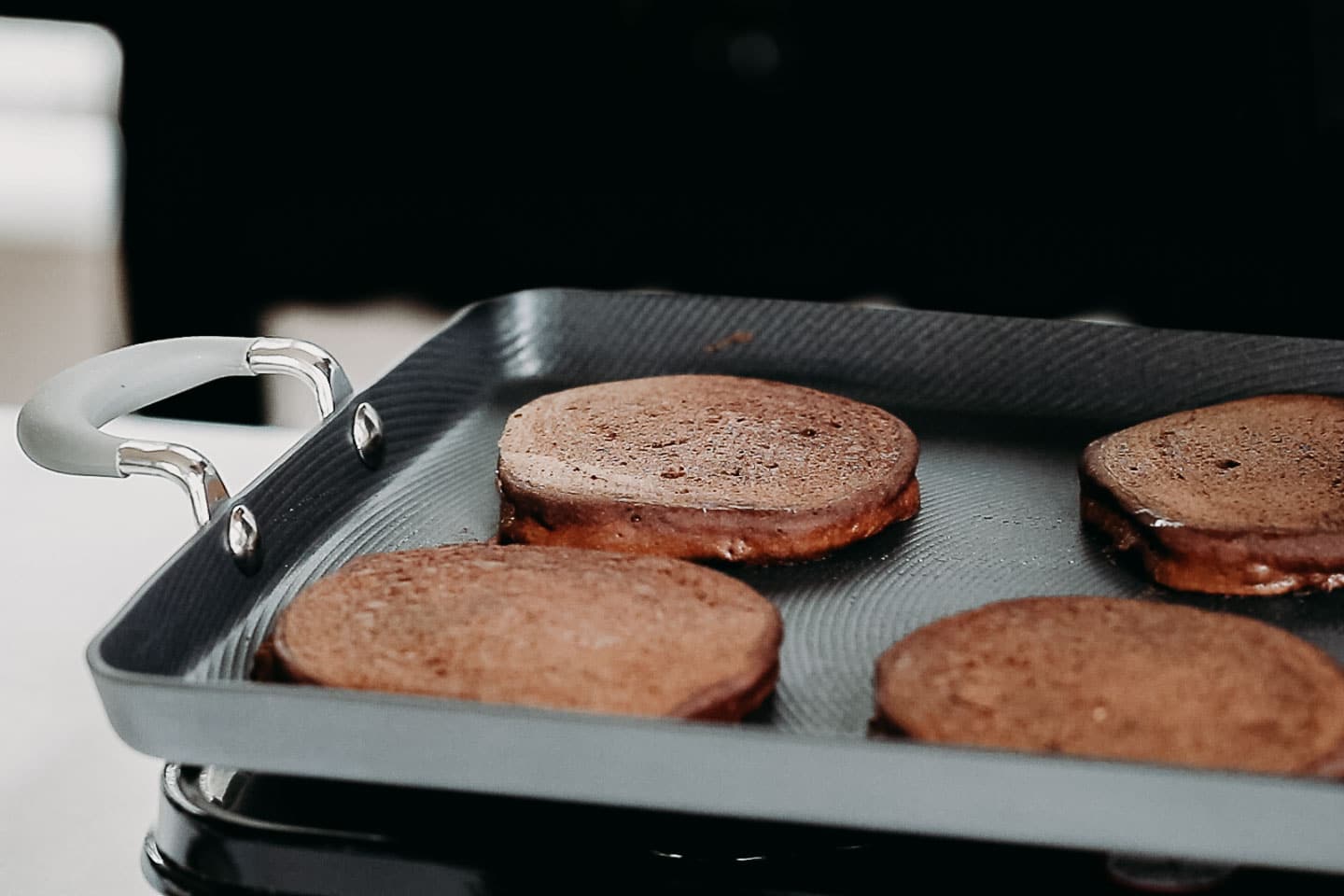A closeup picture of pancakes cooking on a griddle.