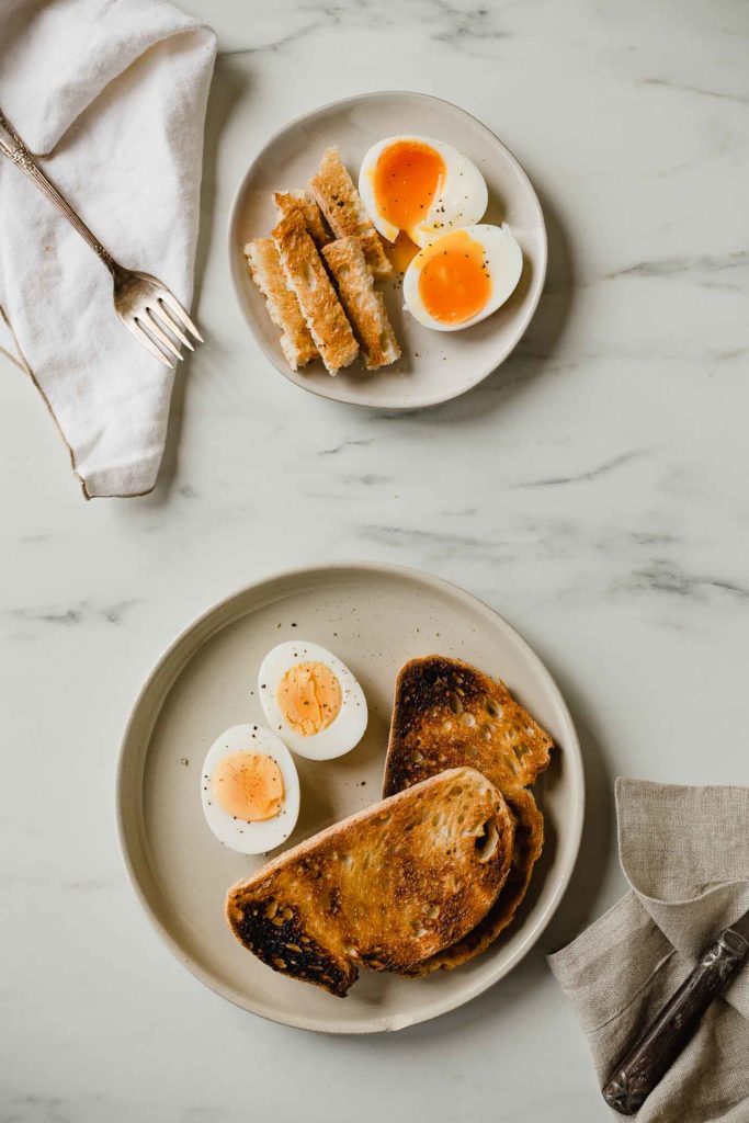 a plate of hard boiled eggs and soft boiled eggs with toast