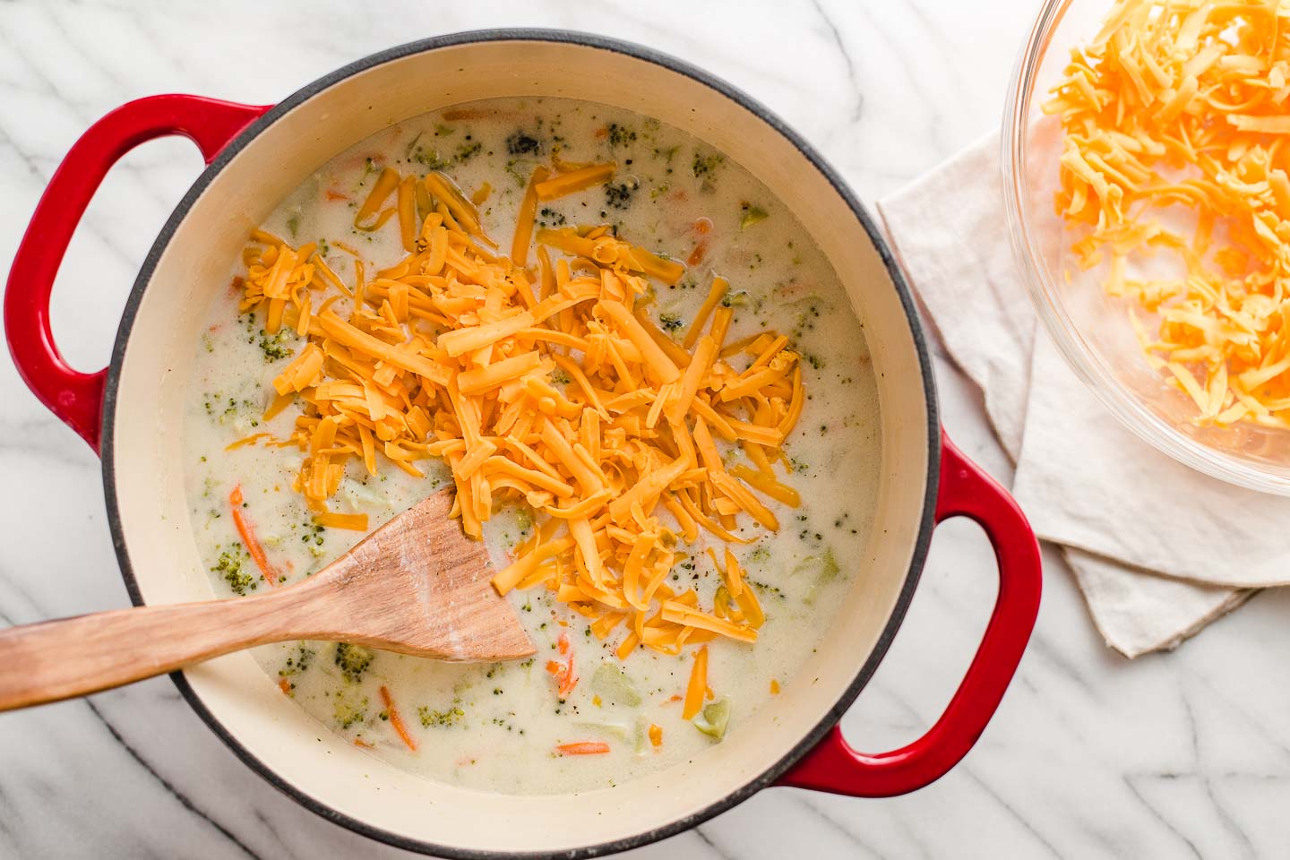 Adding cheddar cheese to the soup.