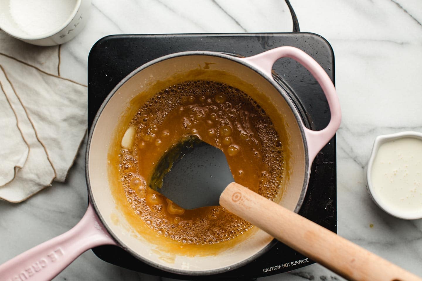Adding butter to browned sugar in a saucepan.
