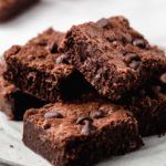 A stack of homemade brownies on a plate.