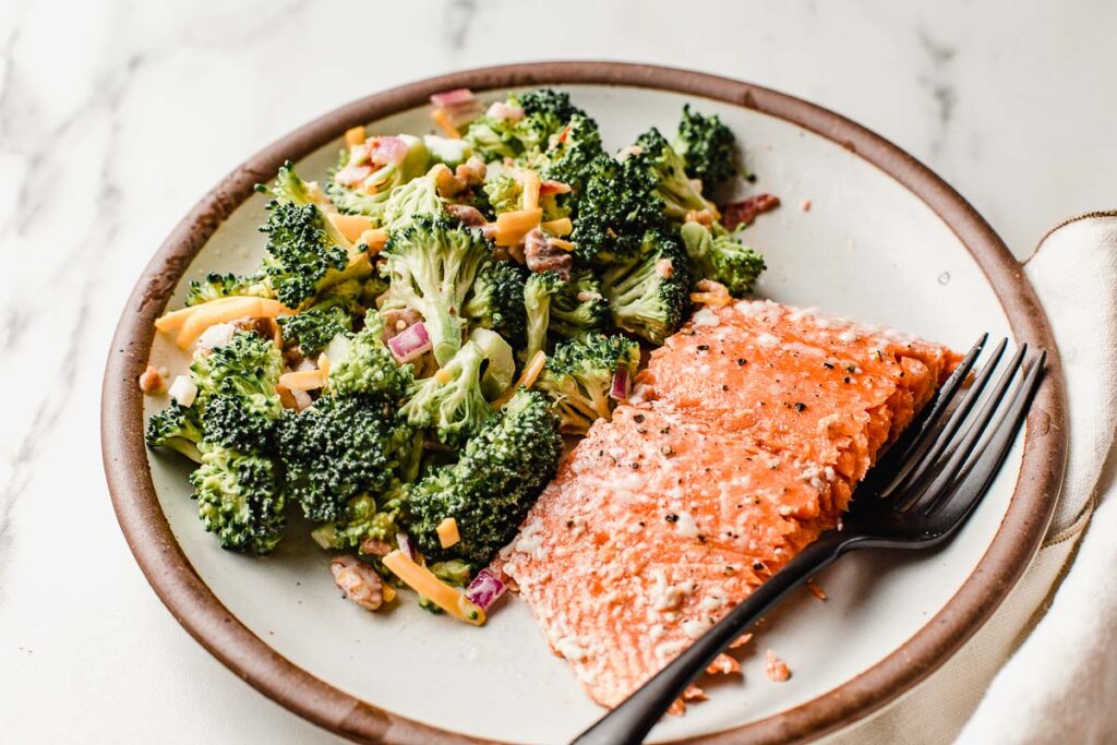 Baked salmon with a side of this low carb broccoli salad on a plate.