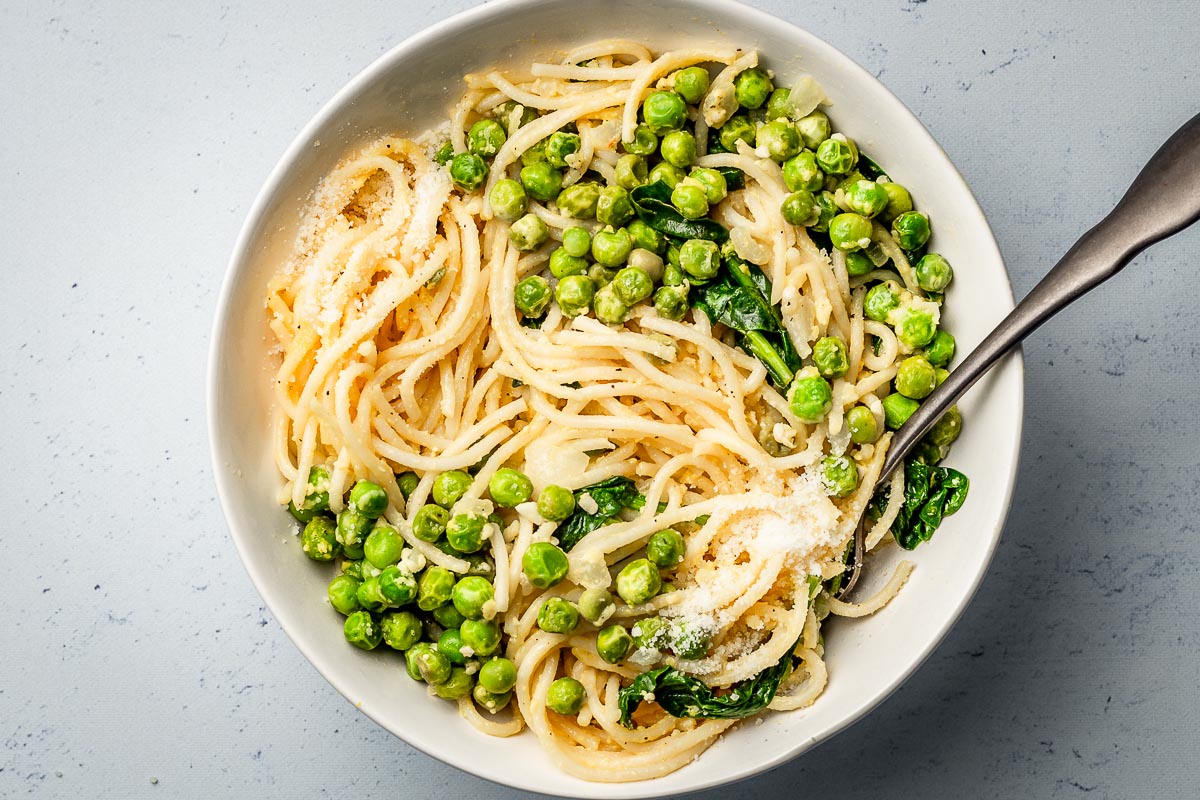 Pasta with peas parmesan and spinach in a bowl.
