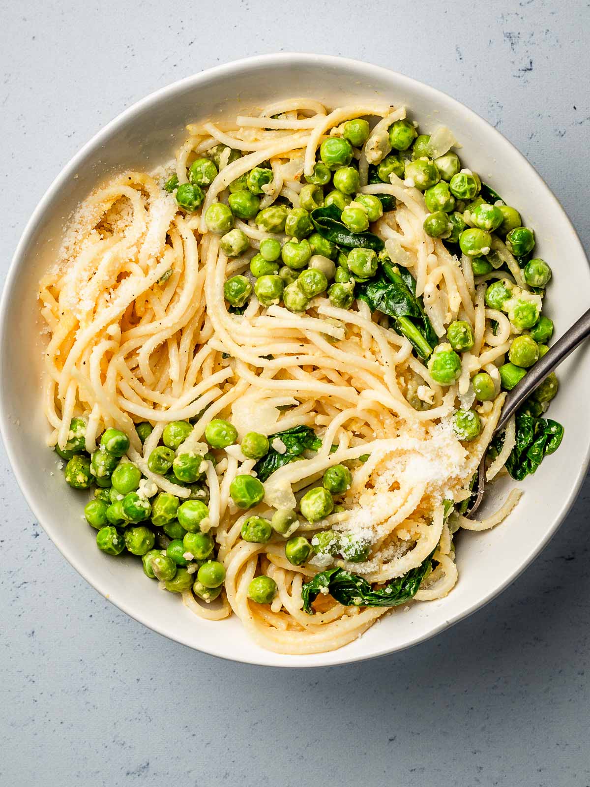 Pasta with peas parmesan lemon and spinach in a bowl.